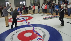 Sue Dyer cuts the ceremonial ribbon on the curling club's new ice. Photo by Bruce Frisch.