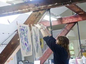 Laura Marciniak, a student, hangs a print in the Art Barn.