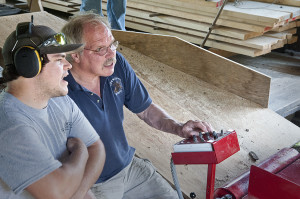 Schuyler Thomson and Wes Gomez, a forest technician at Great Mountain Forest, at the controls of the new sawmill.